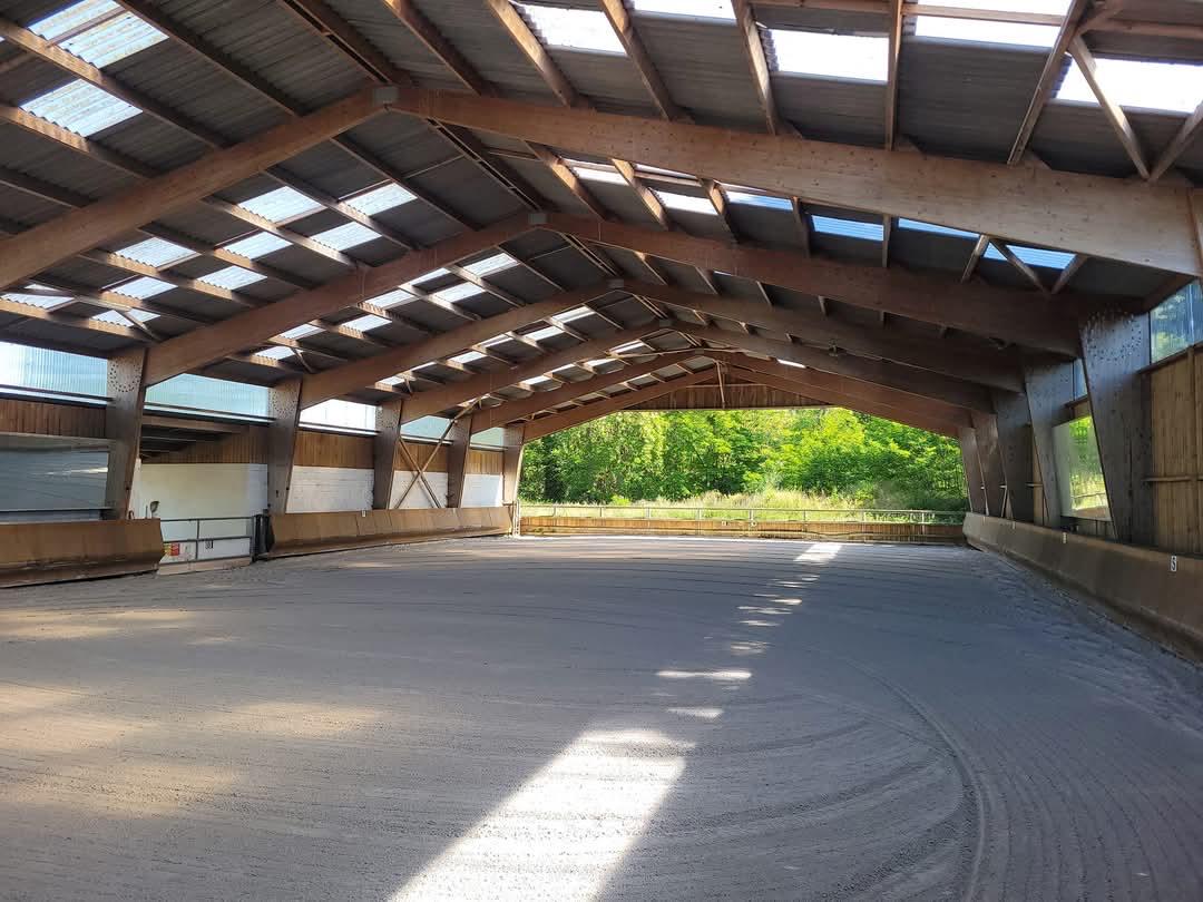 Le manège couvert offre un espace de travail sécurisé et abrité dans les installations équestres du Val-d’Oise.